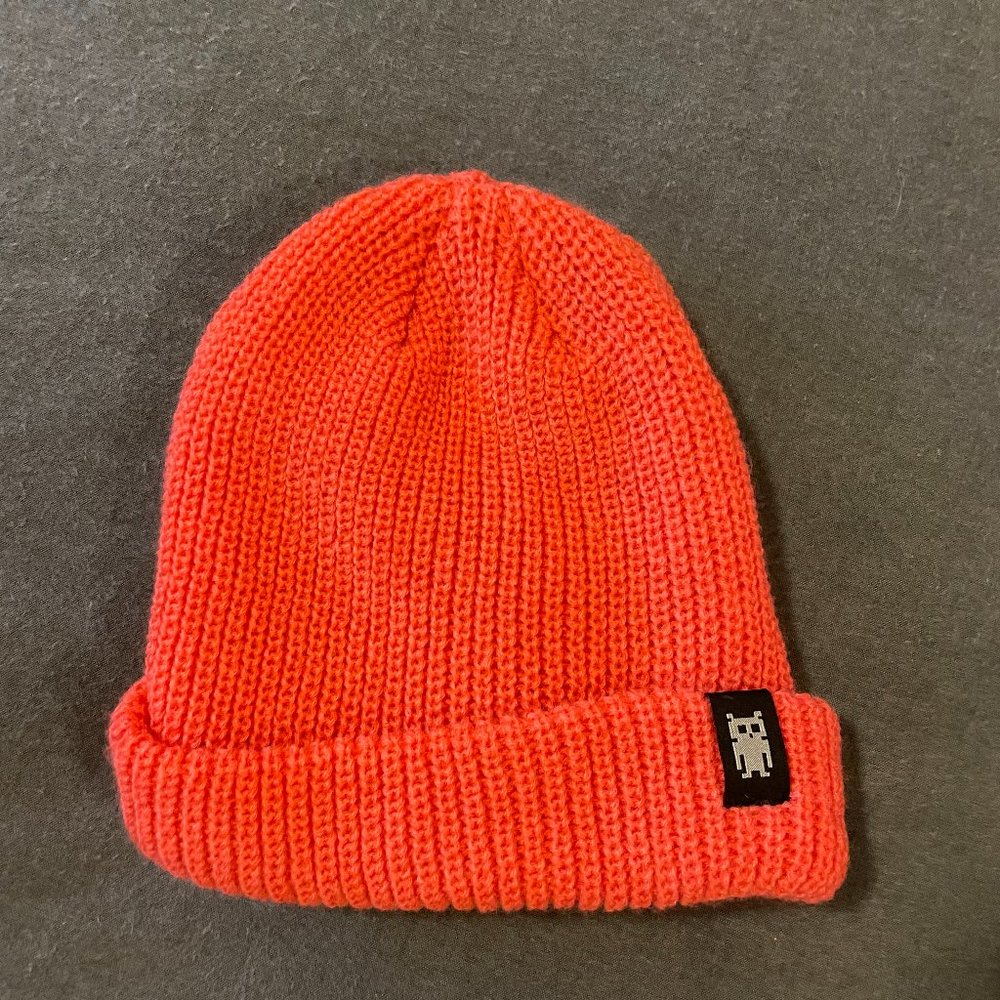 Salmon colored knit beanie with space robot tag